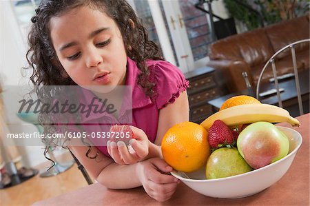 Hispanic girl eating a fresh strawberry