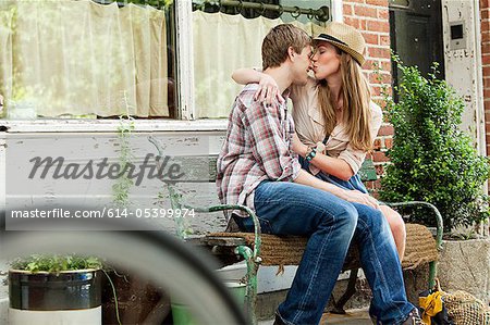Jeune couple s'embrassant sur banc