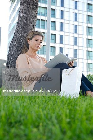 Woman sitting in grass reading book