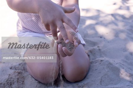 Little girl playing with sand in hands, mid section