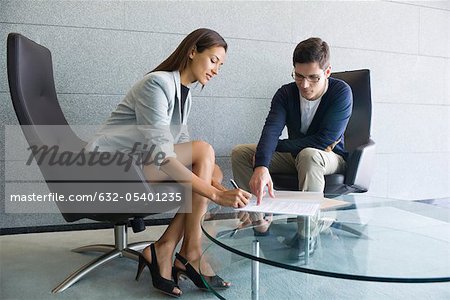 Businessman assisting businesswoman in signing document