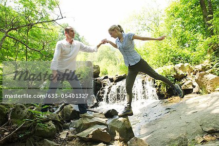 Couple standing on rocks by waterfall