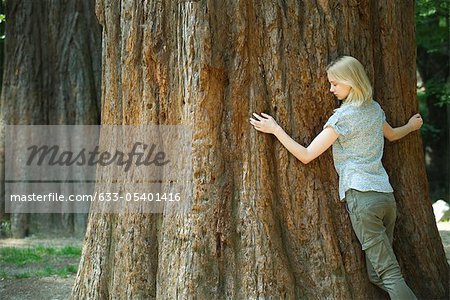 Junge Frau umarmt Baum mit Augen geschlossen