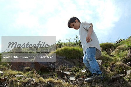 Garçon debout sur une colline rocheuse, vue d'angle faible