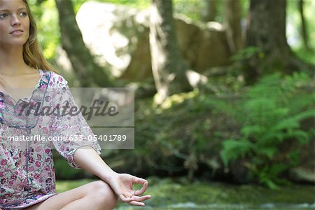 Young woman sitting in lotus position outdoors