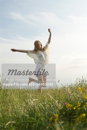 Young woman jumping in meadow