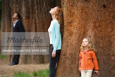 Mother and daughter leaning against tree trunk, breathing fresh air