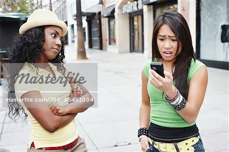 Frau mit Blick überrascht, während Freund schaut missbilligend auf Handy