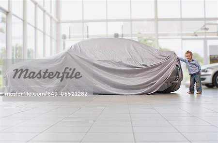 Girl peeking under cloth on car