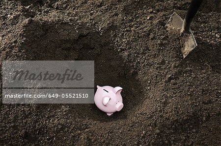 Shovel digging up piggy bank Shovel digging up piggy bank
