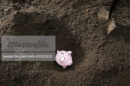 Shovel digging up piggy bank