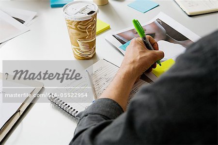 Young man writing on adhesive note