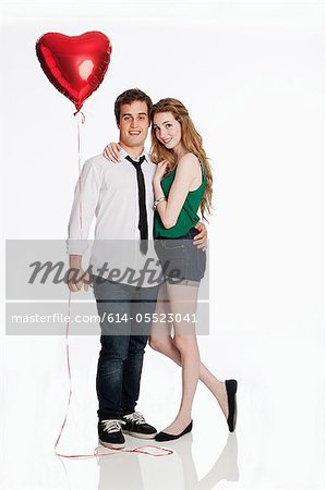 Young couple with balloon against white background