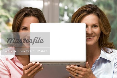 Two happy women holding laptop