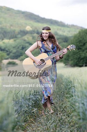 Jeune femme avec une guitare dans le champ de maïs