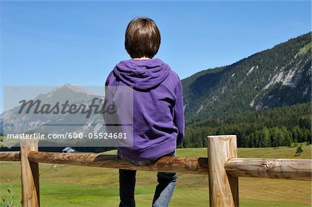 Back View of Boy Sitting on Wooden Fence, Glieres Plateau, Alps, France