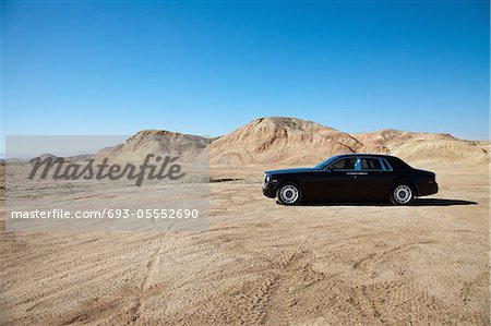 Luxury car parked on unpaved road near mountains