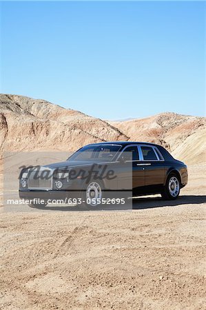 Rolls Royce parked on unpaved road with clear sky