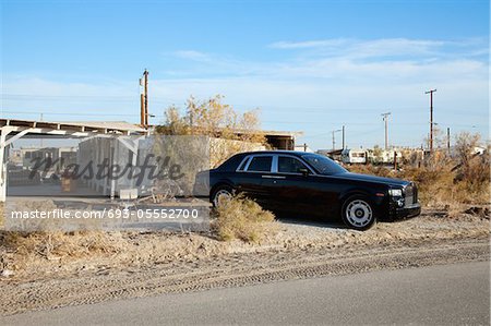 Rolls Royce parked on side of road near abandoned houses