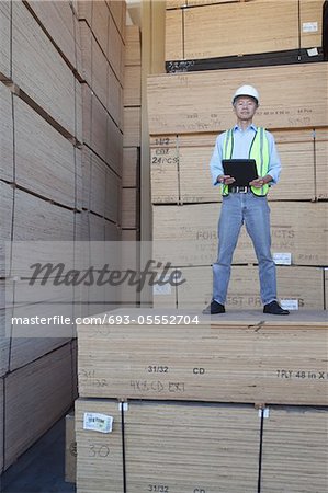 Portrait of a worker standing on stack of plywood