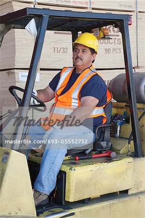 Forklift driver driving in warehouse