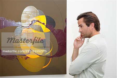 Thoughtful man looking at wall painting in art gallery