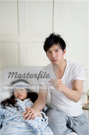 Portrait of young man while woman lying in bed