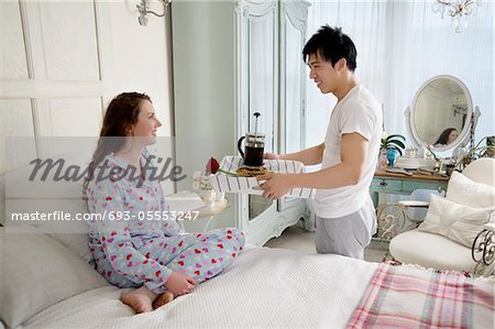 Homme apportant petit déjeuner femme au lit