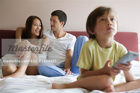 Familie vor dem Fernseher zusammen auf dem Bett