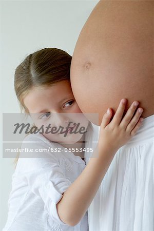 Girl embracing mother's pregnant belly