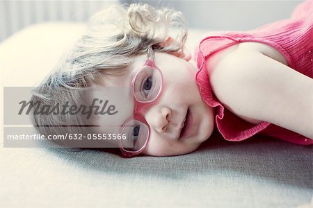 Petite fille avec des lunettes couché sur le côté