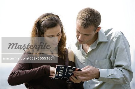 Tourist couple consulting guidebook