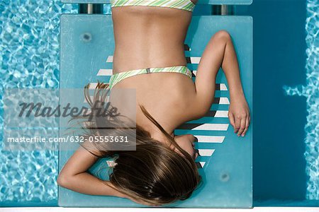 Young woman sunbathing by pool
