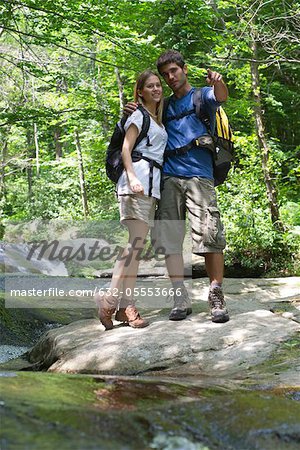 Couple debout par les cours d'eau en bois