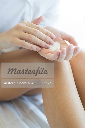 Woman moisturizing legs, cropped