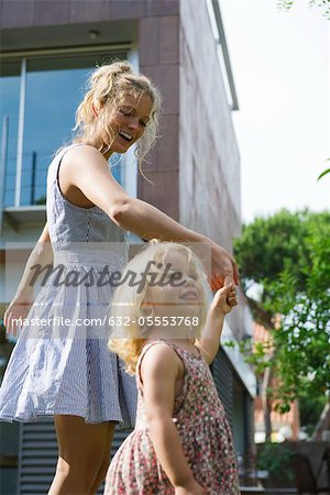Mother and young daughter walking hand-in-hand outdoors