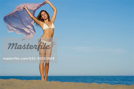Frau am Strand, Schal in Brise draußen halten