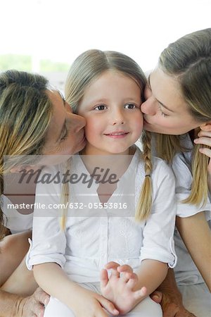 Girl being kissed on cheek by mother and grandmother