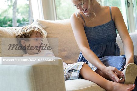 Mother helping young son put on shoes