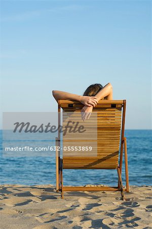 Femme se détendre dans une chaise longue sur la plage