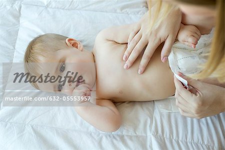 Mother changing baby's diaper, cropped