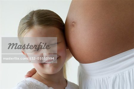 Fille écoute de ventre de femme enceinte de mère