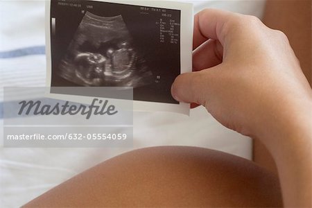 Pregnant woman holding ultrasound, cropped