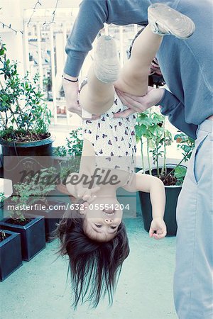 Father holding little girl upside down