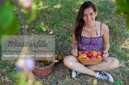 Smiling woman picnicking in orchard