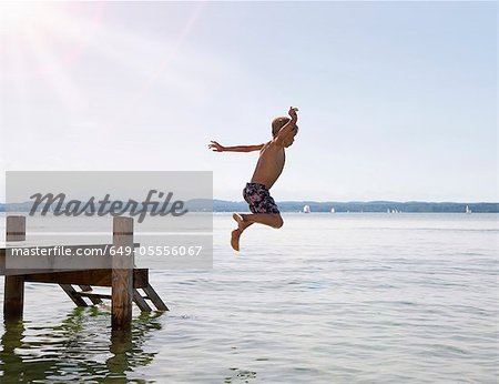 Jeune garçon plongeant dans le lac de quai Jeune garçon plongeant dans le lac de quai
