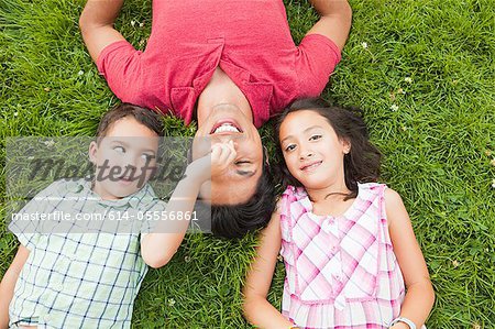 Père couché sur l'herbe avec fils et fille