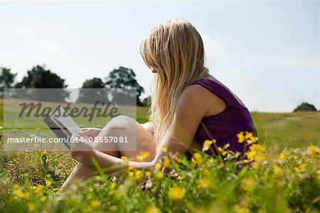 Jeune femme lisant un livre dans un champ