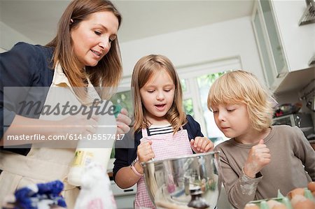 Mid femme adulte cuisson avec fils et fille dans la cuisine