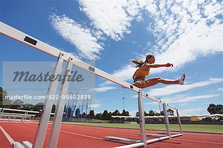 Female Athlete Clearing Hurdles